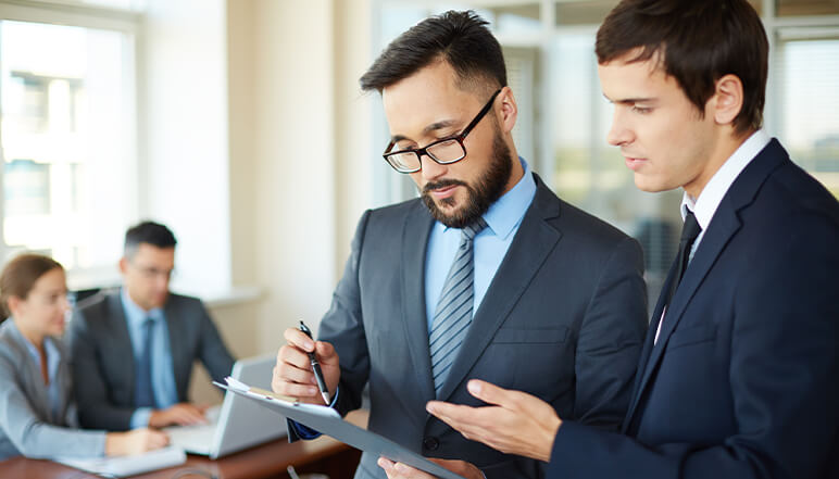 Business professionals discussing compliance strategies in an office setting, highlighting training and support for NDIS regulations.