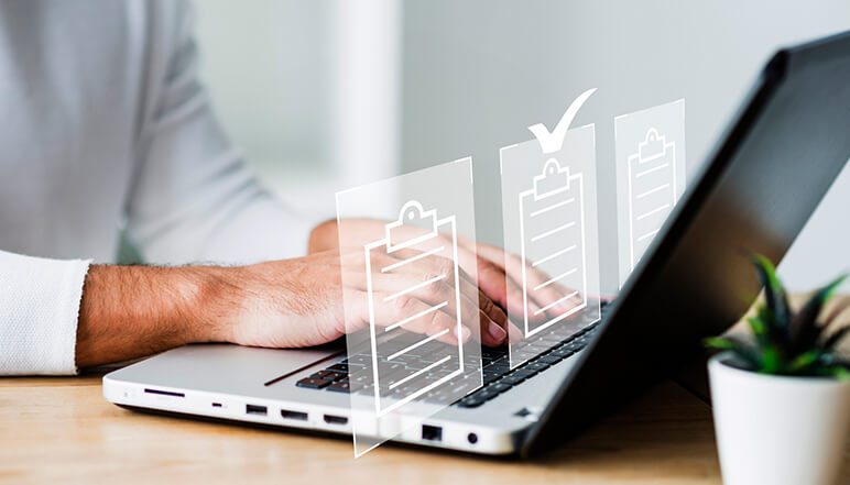 Person typing on laptop with checklist icons, symbolizing documentation management for NDIS compliance services by Compliance Care.